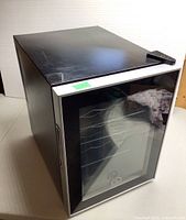 Front angle view showing black wine fridge with glass door and handle on left side.