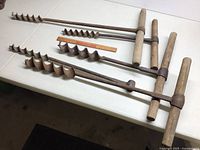 Photo showing all five wood augers laid out on a table with measuring ruler for scale.