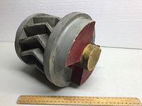 Side view of the wooden sand casting mould showing one circular end with central wooden core and internal radial wooden fins, painted grey and red with light wear.