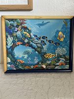 Full view of the framed cross stitch aquarium picture showing various fish and coral under water in colorful detail.