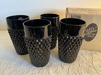 Four black Indiana Tiara diamond point glasses with one showing original sticker, placed on a fabric surface.