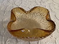 Top view of amber Murano glass ashtray showing scalloped star shape and silver leaf inside glass.