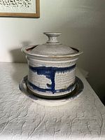Full view of the signed studio pottery steamer pot with lid on the matching bottom plate showing white glaze with blue drip accents and rustic finish.