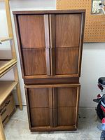 Two stacked mid-century modern nightstands showing vertical cabinet doors and handles