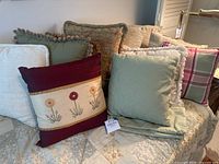 Multiple accent pillows displayed on a bed or couch highlighting the variety of colors and textures in the lot.