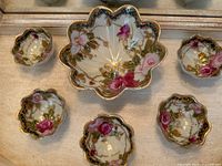 Seven antique Nippon Japan 3-footed rice bowls arranged showing floral pink and white rose patterns with gold detail