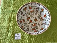 Top-down view of large ceramic bowl showing orange chrysanthemum flowers and butterflies swirling inside.
