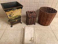 Overall group of three waste baskets and napkin holder with napkins on counter.