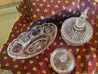 Overview of three crystal and glass bowls and dishes arranged on fabric background.