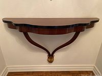 Front view of the wall-mounted floating wood ledge shelf showing shape and decorative gold accent support.