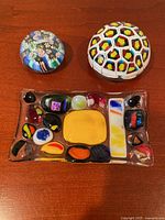 Photo of two glass paperweights and a rectangular glass plate on a wooden surface