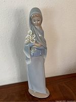 Front view of Lladro figurine showing girl holding Calla lilies, detailing dress and shawl colors.