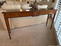 Front view of mahogany console table showing scalloped detail and brass hardware on drawers