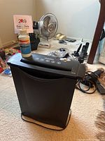 Paper shredder with lubricant bottle on top, showing front and side of shredder