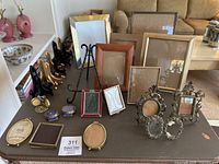 Photo of assorted picture frames on a table, showing various sizes and shapes including ornate and miniature frames.