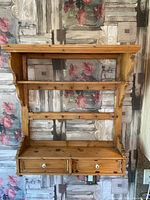 Front view of vintage pine wood shelving unit displaying shelves, hooks, and drawers.