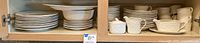 Photo of stacked plates, bowls, cups and serving pieces showing complete set condition and quantity.