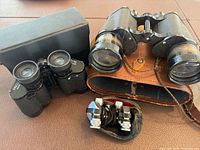 Photo showing three pairs of binoculars of varying sizes and styles on a table surface