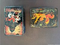Both lacquer boxes showing painted lids with Asian art scenes