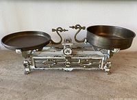 Front view of vintage cast-iron and brass kitchen scale with two pans on either side and ornate metalwork base.