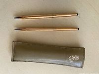 Full view of the ballpoint pen and mechanical pencil set alongside the green faux leather case with a floral design.