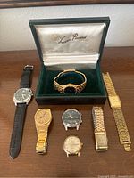 Seven vintage men's watches arranged on table including one in original Lucien Piccard box