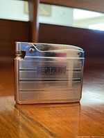 Side view of the silver tone Ronson Adonis lighter etched with F.L.L.