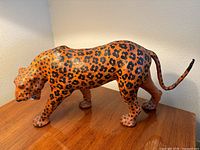Full side view of the vintage wrapped leather leopard statue showing the spotted pattern and form.