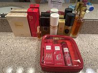 Photo showing razasi Shuhrah perfume box, Giorgio Red perfume, Chanel Coco, Lanvin/Clinique aromatic fragrances, and Umberto travel hair care set in red pouch.