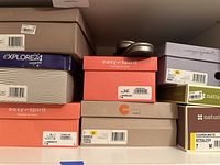 Photo showing stacked shoe boxes from Easy Spirit, Naturalizer, and Explore24 brands, various sizes including 7 and 7.5, indicating original packaging.
