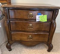 Front view of the wooden bedside table showing three drawers closed with brass hardware.