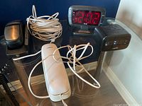 Group shot: two alarm clocks, two phones, cords visible