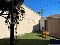 String lights hanging from patio structure showing multiple clear bulbs on black cord