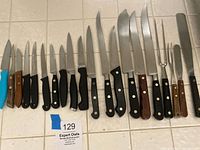 Full lineup of knives and carving fork on tiled surface