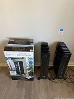 Two black electric radiators next to their boxes