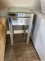 Full view of mirrored nightstand positioned between sofa and chair