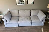 Full front view of the three-section grey modular couch against wall