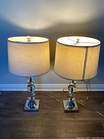 Front view of both glass table lamps with shades illuminated