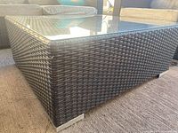 Corner view of wicker coffee table showing glass top and woven texture