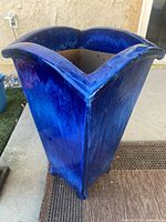 Full view of tall blue drip-glazed terracotta planter on pedestal feet