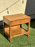 Three-quarter view of nightstand showing drawer, shelf, legs
