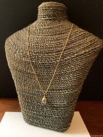Necklace displayed on woven bust form showing full length and pendant drape