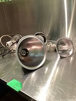 Photo of the three clamp lights arranged on a reflective metal surface, showing their different sizes and reflective interiors.