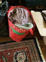 Red bag filled with various clothing items including a visible light brown plaid shirt folded on top.