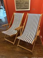 Two wooden lounge chairs with blue and white striped fabric slings in upright position.