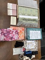 Collection of assorted textiles, ribbons and decorative box spread on a table