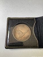 Close-up of the commemorative silver dollar coin featuring flying goose design inside plastic case.