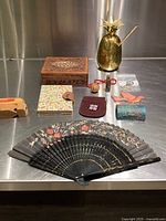 Overview of eclectic collectible decorative items arranged on metal surface, showing all items in the lot