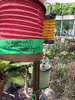 Four colorful Turkish hanging lanterns seen hanging in garden setting with visible ribbed textured bodies and metal tops with perforations and adornments.