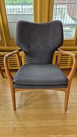 Front view of gray upholstered armchair with wooden frame.